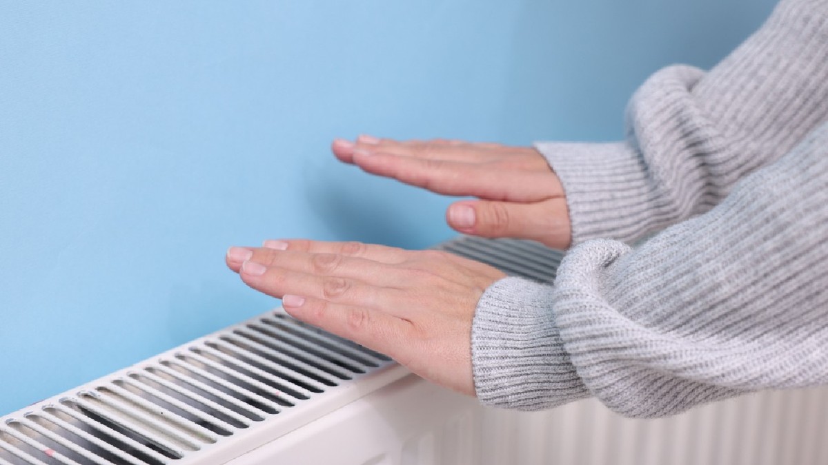 Femeie încălzindu-și mâna lângă radiator interior, closeup