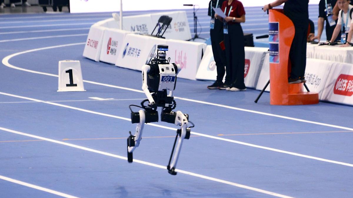 Un robot umanoid aleargă pe o pistă albastră de atletism.