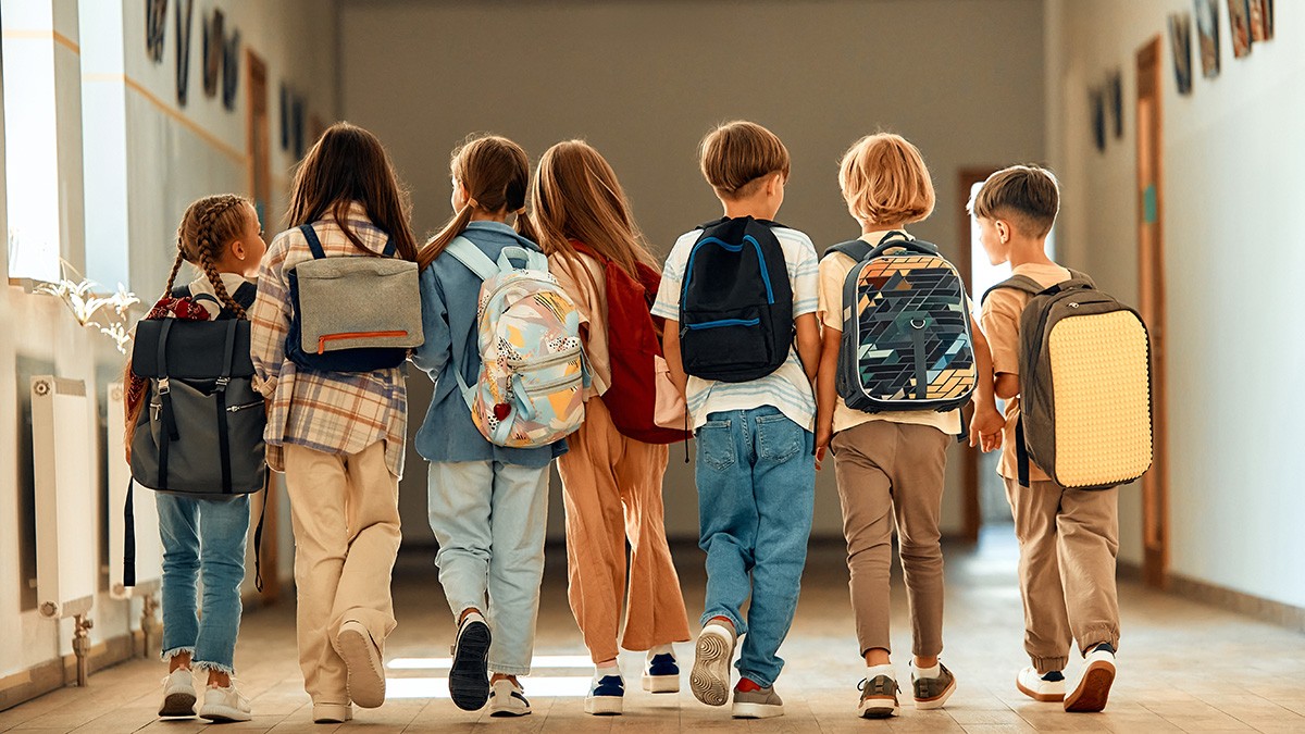 Un grup de școlari cu ghiozdane se plimbă pe coridorul școlii în timpul pauzei.