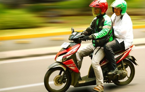 Doi oameni pe un scuter merg pe strada
