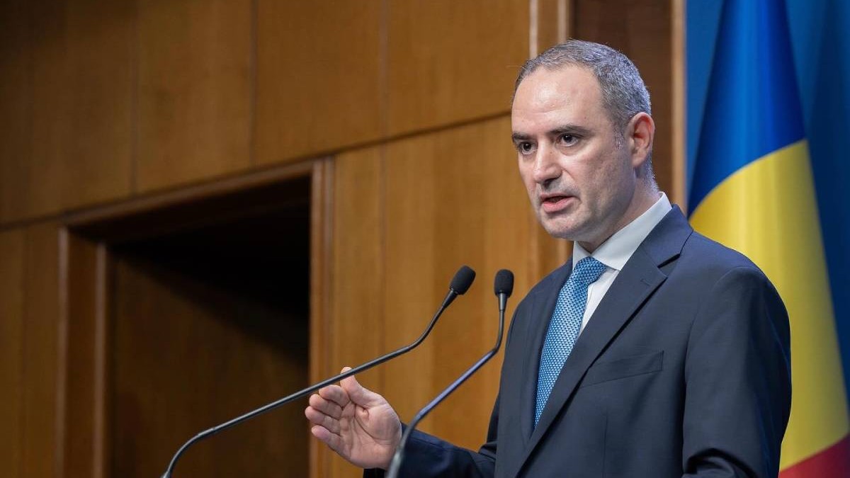 Ministrul Finanțelor, Alexandru Nazare, în timpul unei conferințe de presă la Guvernul României, vorbește la microfoane și are o mână ridicată, în timp ce explică ceva