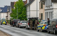 Mașini de poliție parcate în fața unei case din Germania, în timpul unei interventii