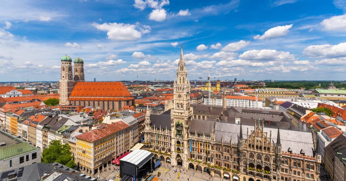 Primăria Nouă și Biserica Frauenkirche într-o zi de vară însorită, cu turiști în Marienplatz. Panoramă asupra centrului vechi din München, Bavaria, văzută din turnul Alter Peter.