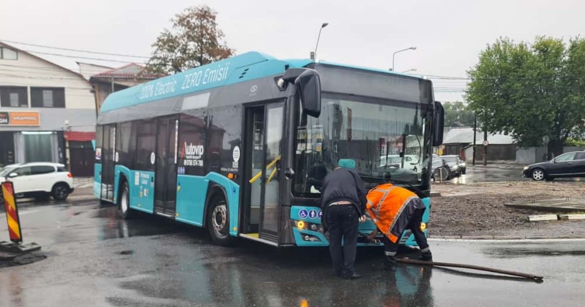 autobuz Transurb împotmolit în nămol în Galați. Doi bărbați în geci negre și portocalii încearcă să îl împigă, 8 octombrie 2025