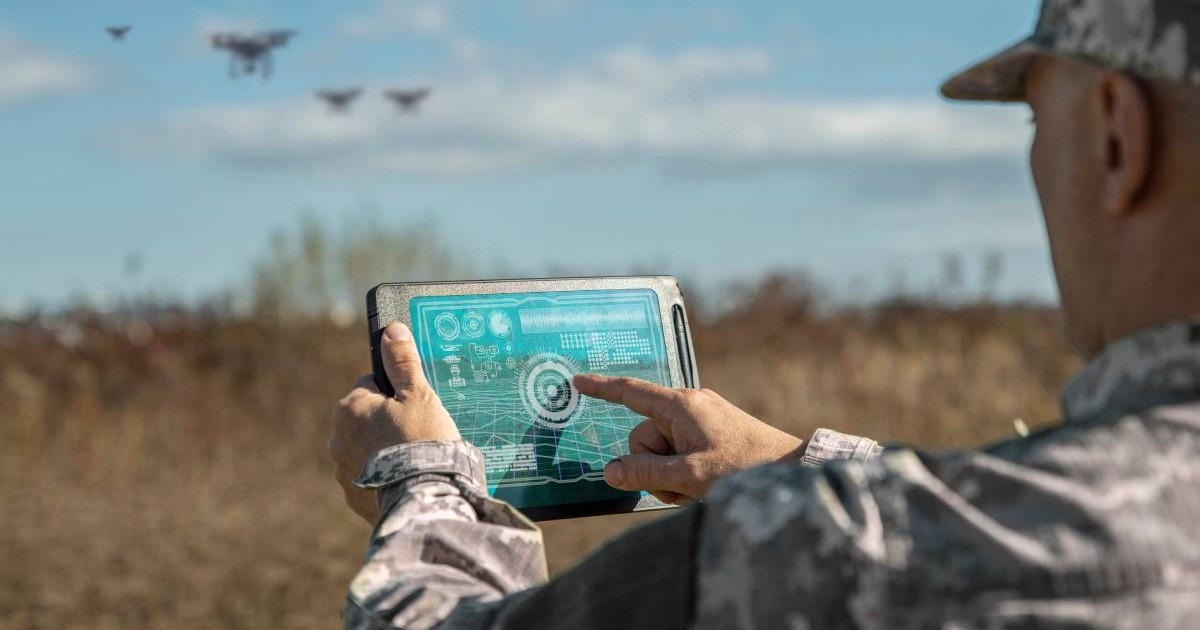 Un militar în timp ce urmărește mișcările unor drone, pe ecranul unei tablete.