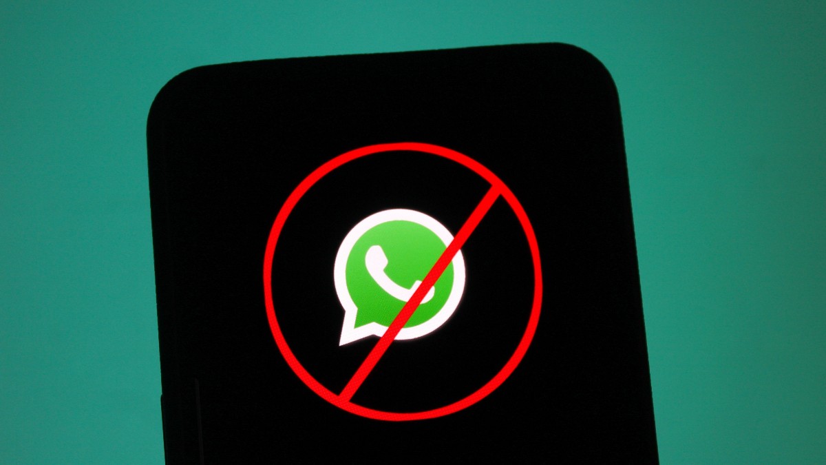 Imaginea arată sigla WhatsApp pe un ecran de telefon, încadrată de un cerc roșu tăiat oblic, simbolul universal al interdicției. Fundalul întunecat evidențiază mesajul vizual clar: aplicația este interzisă sau blocată.