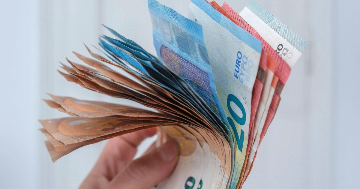 O persoană care ține bancnote de euro în mână