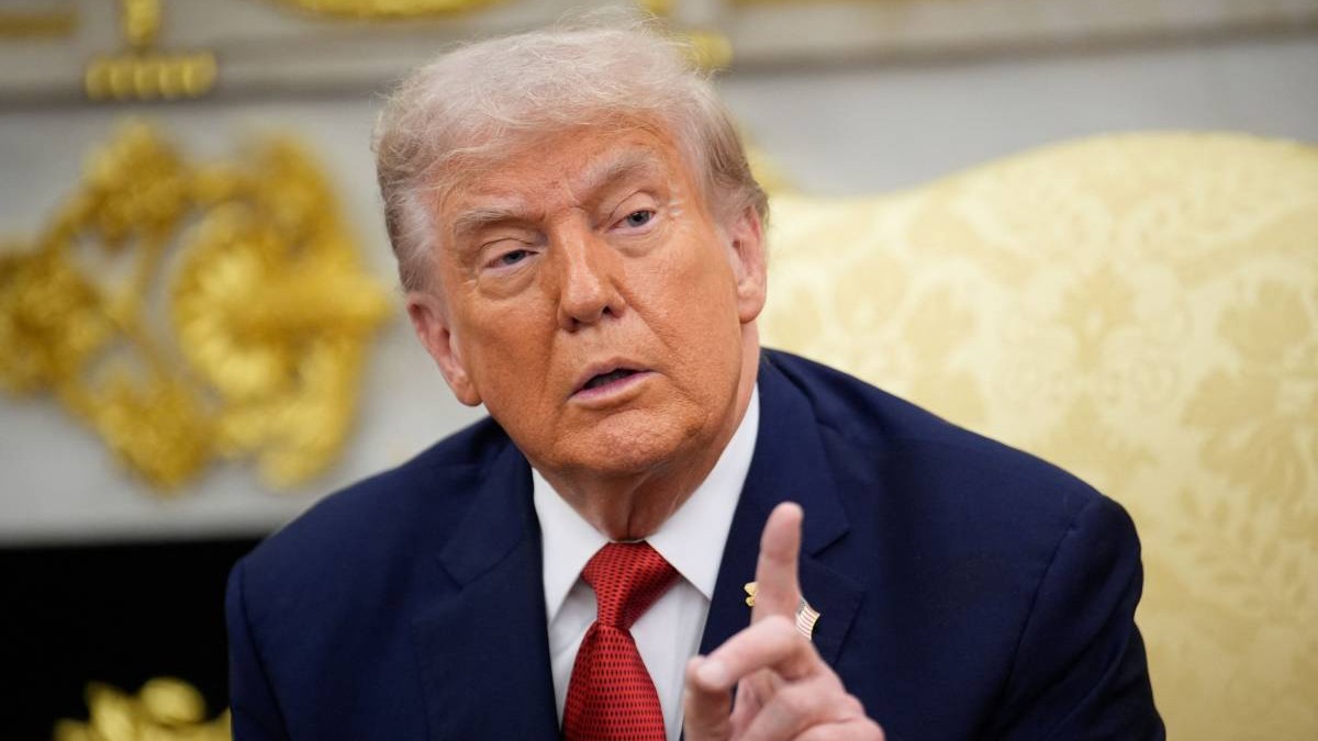 Președintele american Donald Trump stând pe canapeaua galbenă din Biroul Oval, ține degetul arătător ridicat și explică ceva