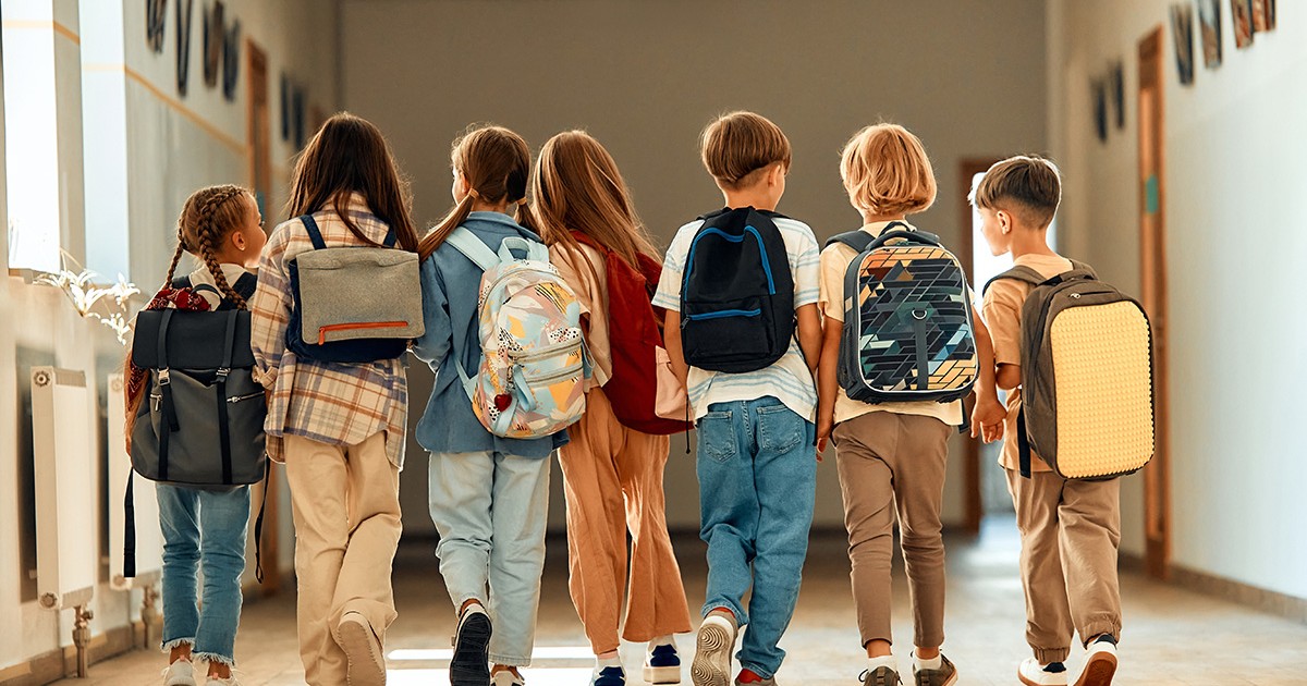 Un grup de școlari cu ghiozdane se plimbă pe coridorul școlii în timpul pauzei.