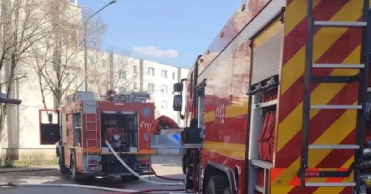Două mașini de pompieri care intervin pentru stingerea unui incendiu dintr-un bloc