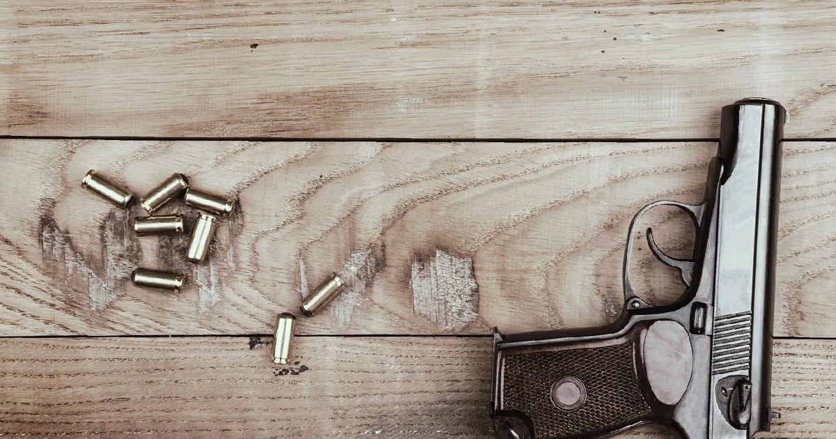 Pistol cu gloanțe și cartușe pe suprafața de lemn, vintage