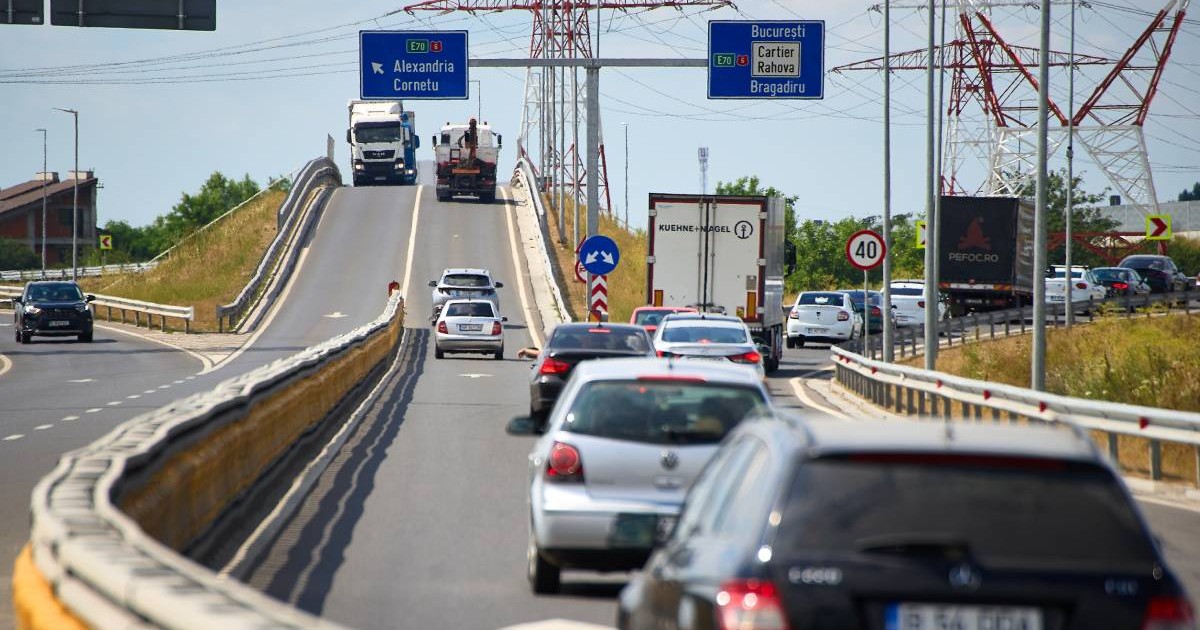 Mașini în timp ce merg pe o șosea de centură din România, deasupra lor sunt indicatoarele rutiere