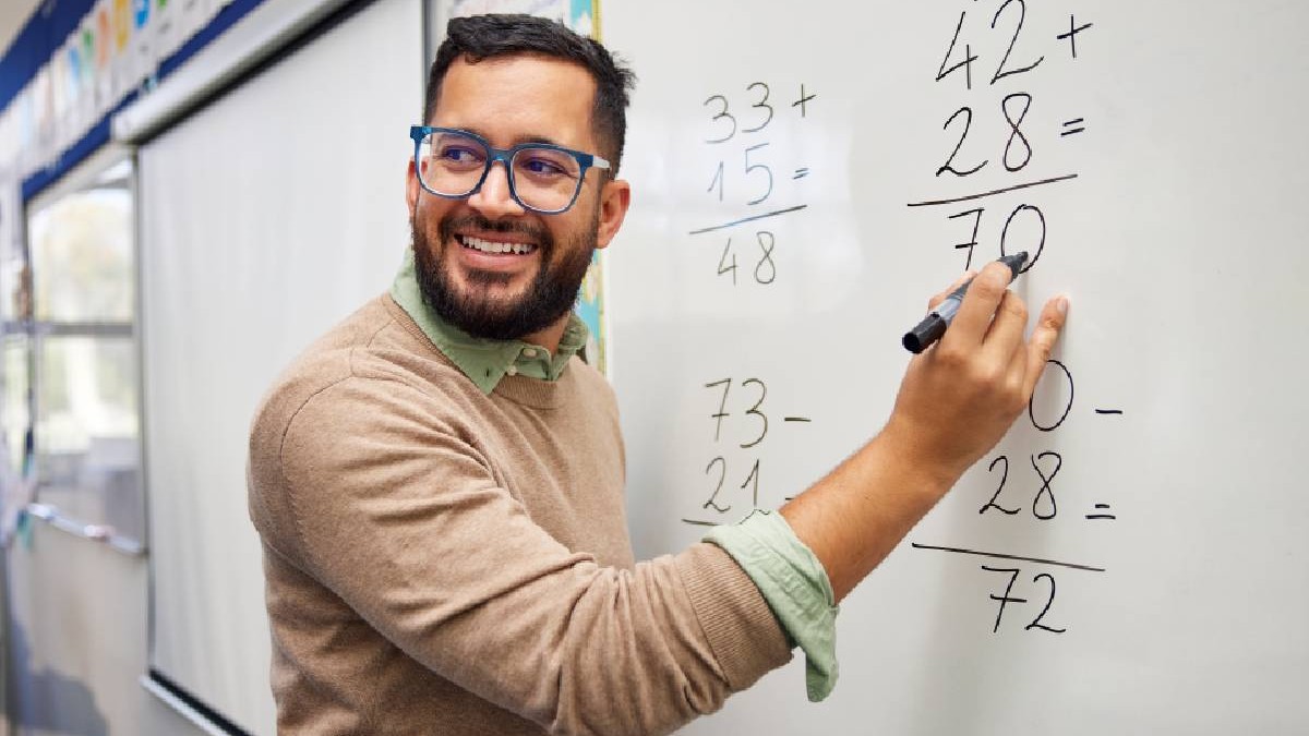 profesor de matematică face calcule pe tablă în clasă