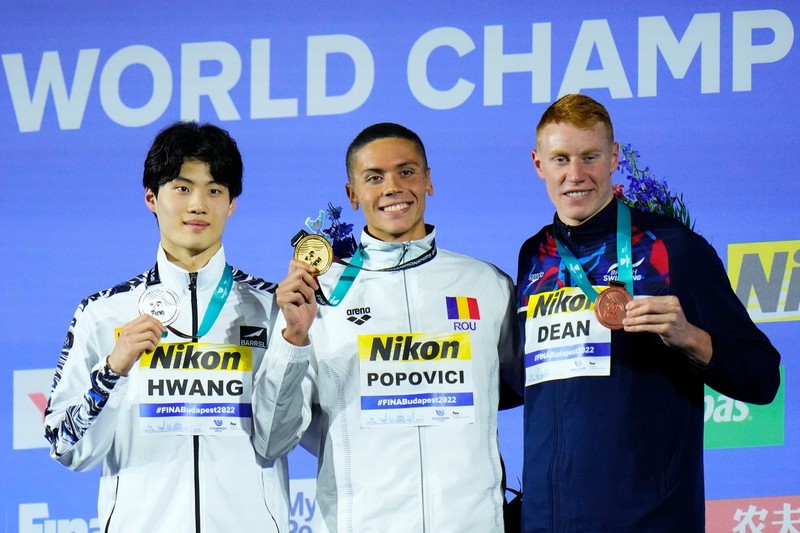 David Popovici pe podium, între sportivul coreean Hwang Sunwoo, care a luat argintul la proba de 200 de metri liber, și britanicul Tom Dean din, care a luat bronzul | Foto: Profimedia