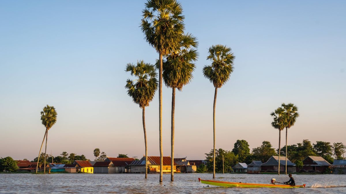O barcă pe Lacul Tempe la apus, înconjurat de palmieri și case plutitoare din satul Sulawesi, Indonezia, 18 august 2025