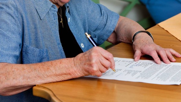 O  femeie pensionară semnează un contract. Poză cu caracter ilustrativ. Sursă foto: Getty Images