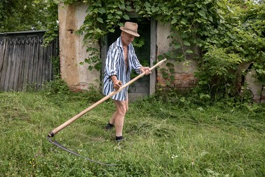 Unul dintre vecinii lui Alexandru coseşte iarba din faţa casei părinteşti