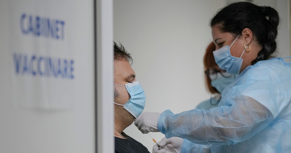 O asistentă medicală vaccinează un pacient, într-un spital