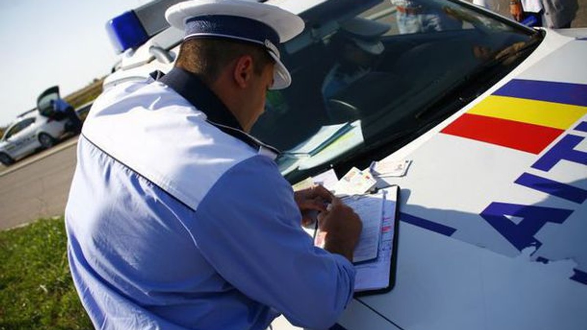MAI a scos la concurs peste 500 de posturi. Polițist rutier care dă o amendă unui șofer, pe capota mașinii de poliție