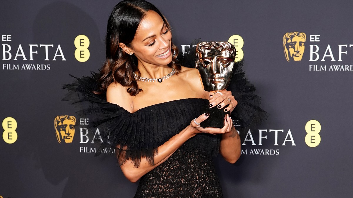 Zoe Saldana ține în mână Premiul BAFTA primit pentru cea mai bună actriță în rol secundar.
