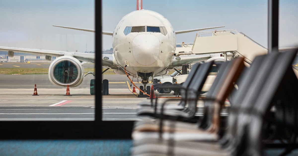 Un avion fotografiat din interiorul unui aeroport, pe pistă.