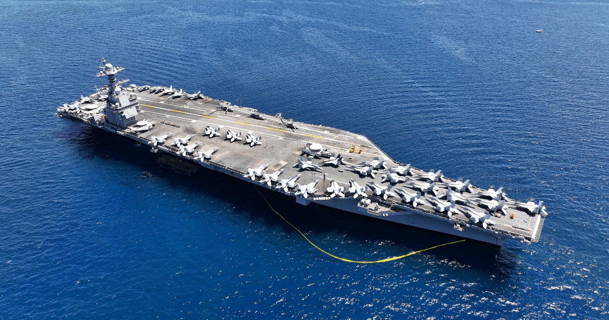 Imaginea surprinde portavionul USS Gerald R. Ford navigând pe mare, cu puntea plină de avioane de luptă aliniate pentru operațiuni aeriene. Văzut de sus, colosul militar evidențiază dimensiunea impresionantă și complexitatea tehnologică a celei mai moderne nave din flota SUA.