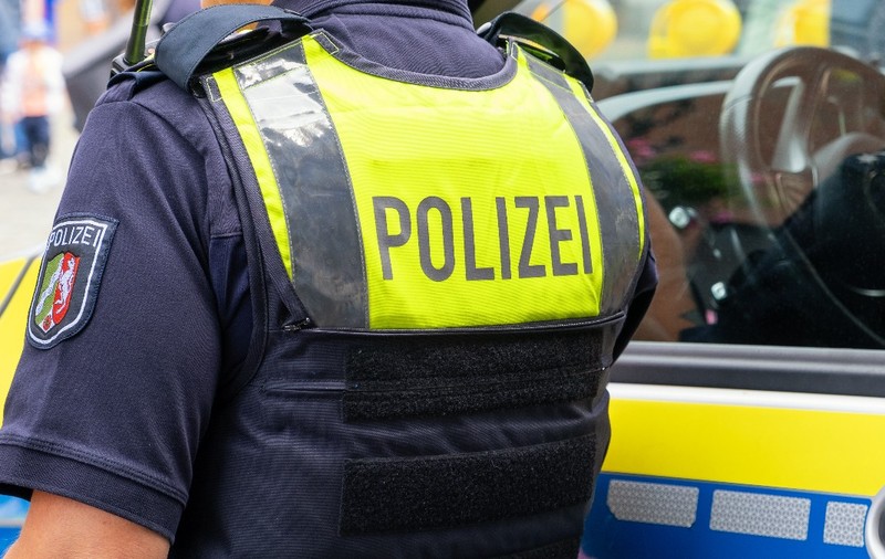 Un polițist văzut de la spate lângă o mașină de poliție