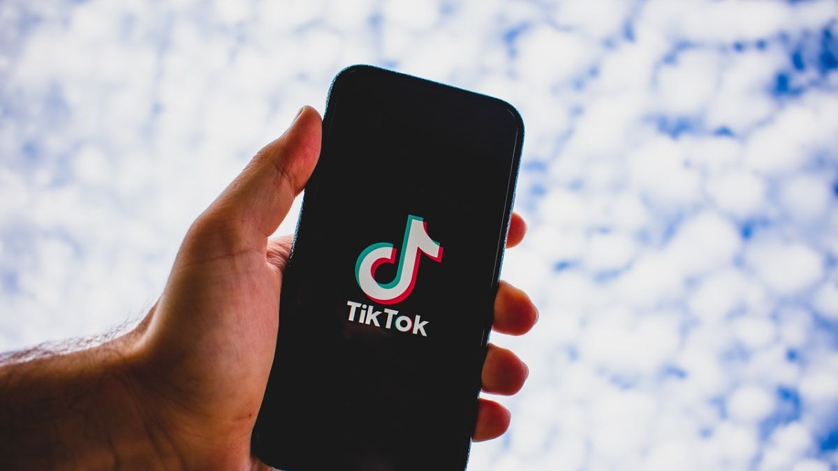 Un bărbat ține în mână un telefon , pe ecranul căruia este TikTok și apare sigla acesteia. Foto: pixabay.com