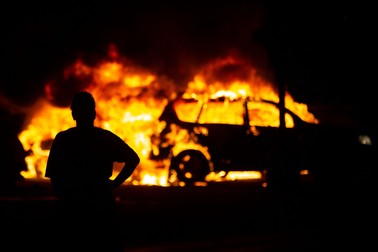 O persoană stă în fața unei mașini în flăcări, în timpul ciocnirilor violente dintre manifestanți și poliție în timpul protestului organizat după moartea lui Jacob Blake | Foto: Hepta/Chris Juhn/ZUMA Wire/dpa