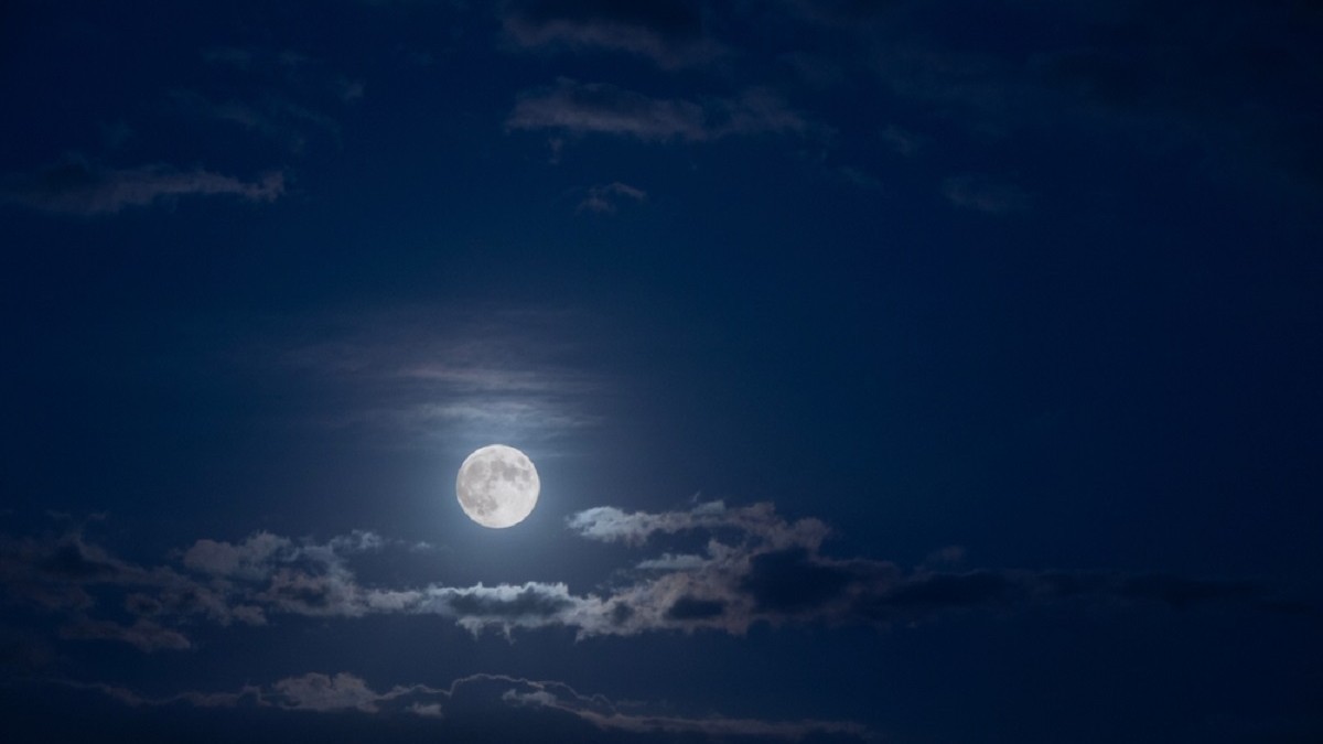 Luna plină în Berbec, 26 septembrie 2026 - Luna plină pe cerul nopții, printre nori răsfirați.