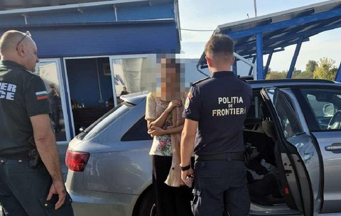 Doi polițiști de frontieră, unul din Bulgaria si unul din România, discută  cu o femeie langa o masina gri, la vama Calafat