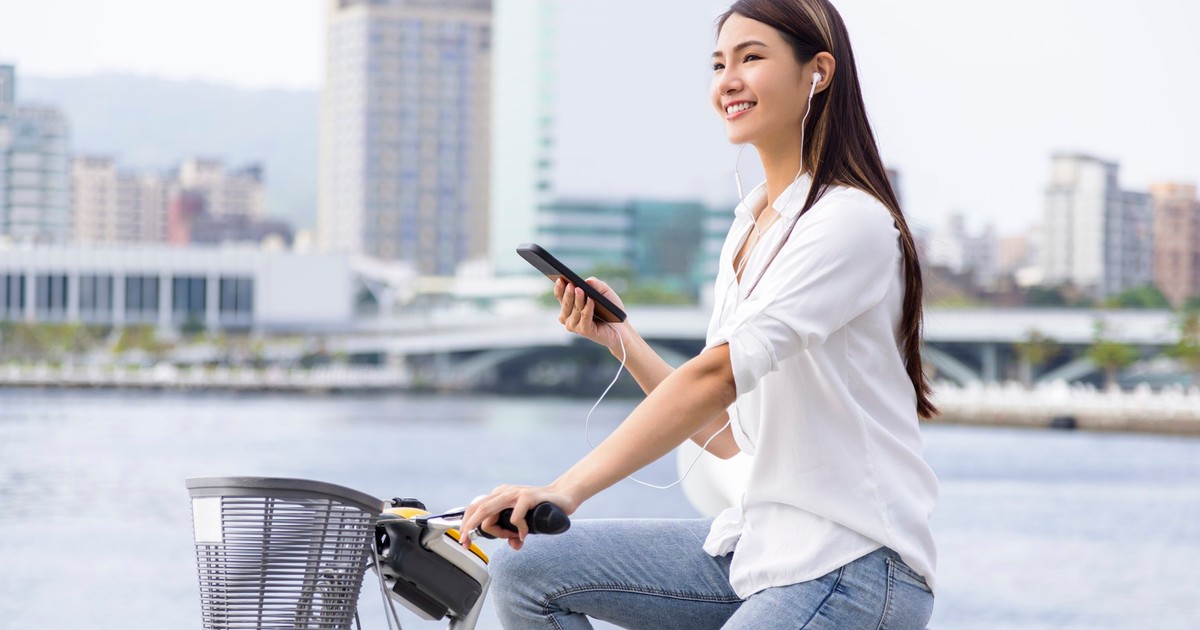 Tânără care utilizează telefonul în timp ce merge pe bicicletă