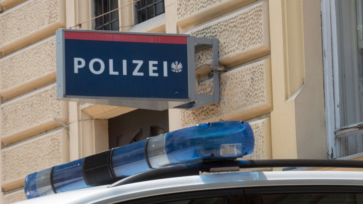 Sigla Poliției din Austria se vede pe peretele instituției, iar sub ea este o mașină a polițiștilor, cu girofar
