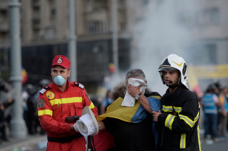 Un protestatar afectat de gazele lacrimogene, condus la ambulanță de paramedici| Foto: Hepta
