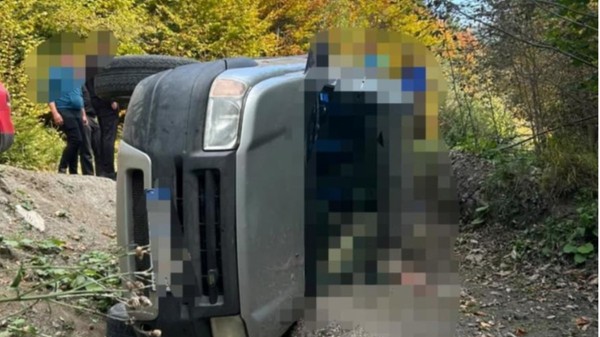 O mașină răsturnată pe drum forestier. Aceasta are numerele de înmatriculare și parbrizul blurate