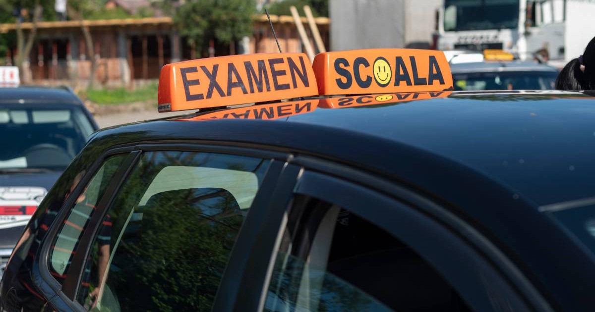 Mașina de Școală auto, neagra, cu doua casete portocalii pe plafon, pe una scrie EXAMEN, pe una ȘCOALA