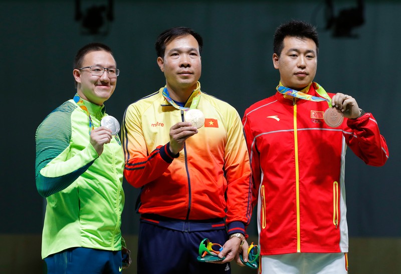 epa05459500 Hoang Xuan Vinh (C) of Vietnam poses with his gold medal on the podium after winning the men's 10m Air Pistol final of the Rio 2016 Olympic Games Shooting events at the Olympic Shooting Centre in Rio de Janeiro, Brazil, 06 August 2016. Hoang Xuan Vinh won ahead of second placed Felipe Almeida Wu (L) of Brazil and third placed Pang Wei (R) of China. EPA/VALDRIN XHEMAJ