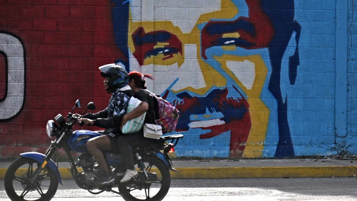O motocicletă trece pe lângă un graffiti care îl înfățișează pe președintele Venezuelei, Nicolas Maduro, în Caracas, pe 3 decembrie 2026.