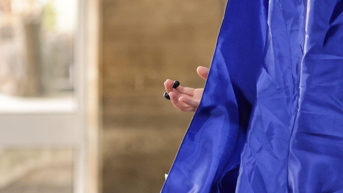 mâna unui alegător care ține o stampilă în mână, după o perdea din cabina de vot
