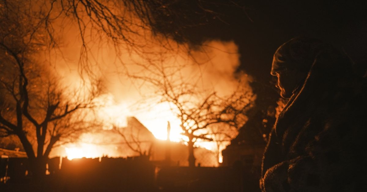 O femeie se uită la o clădire în flăcări după bombardamentul rus în satul Ivanivka de lângă Bahmut din zona Donețk, Ucraina, 2 ianuarie 2023