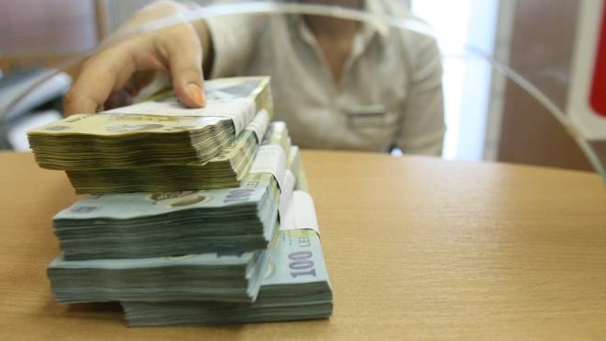 Cum va funcționa amânarea ratelor: cei interesați trebuie să depună o declarație pe proprie răspundere la bancă. Teancuri de bani pe ghișeu la bancă