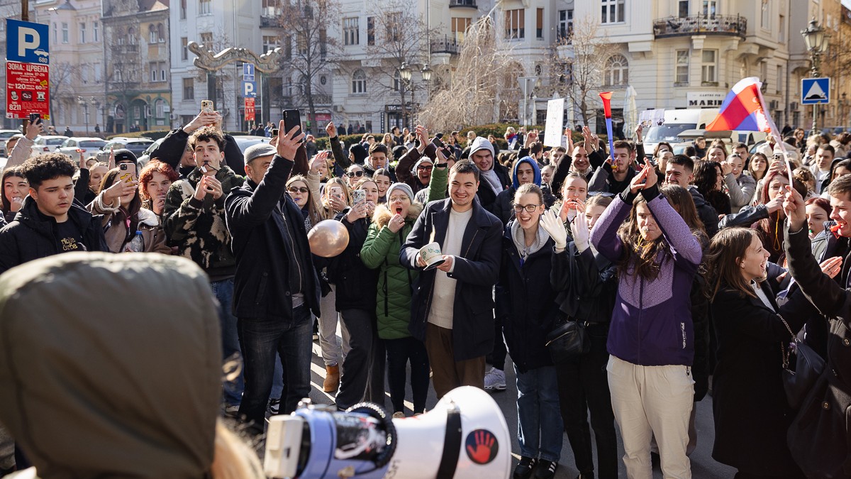 Protest studenți Novi Sad. In imagine se vede o multime de studenti care protesteaza, ia rin fata lor o persoana cu portavoce care pare sa dea tonul scandarilor
