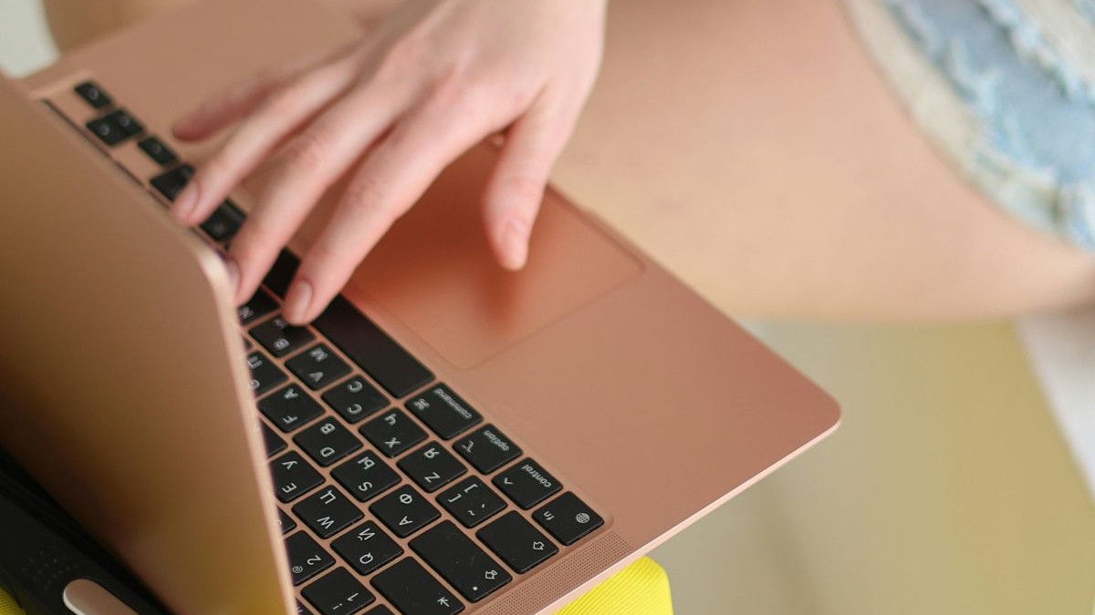 O femeie are o mână pe laptop care stă pe o masă