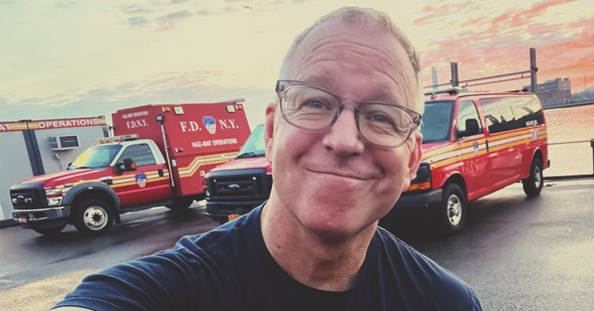 Jonathan Kleisner, milionarul care a lăsat baltă afacerile ca să devină paramedic, zâmbește având pe fundal mai multe ambulanțe, iunie 2025