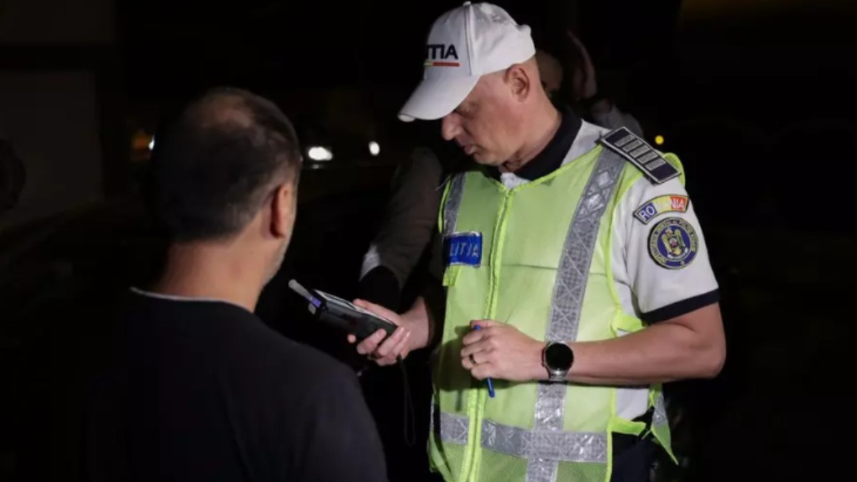 Un polițist care testează cu aparatul alcooltest un bărbat.