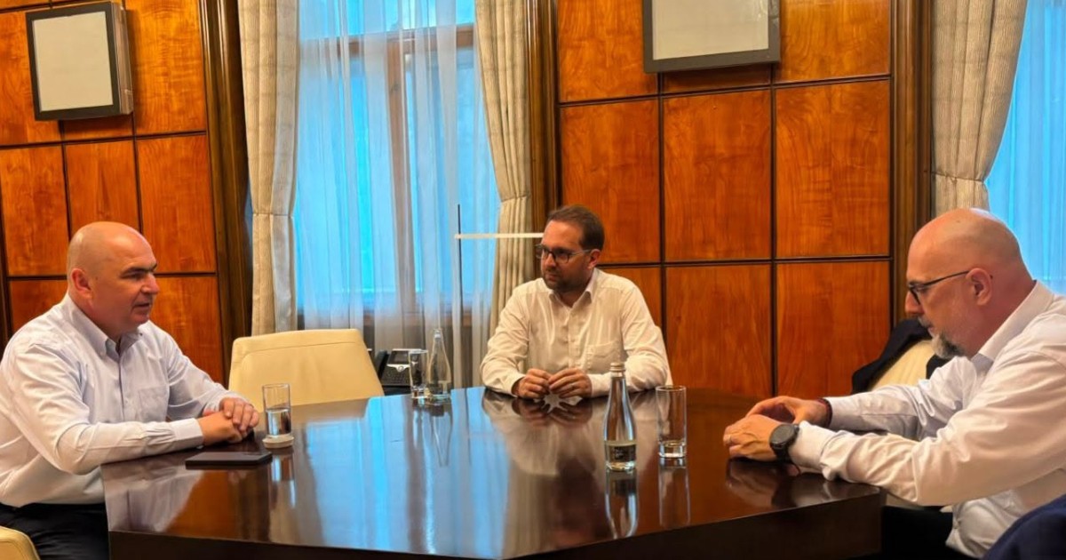 Ilie Bolojan, Dominic Fritz și Kelemen Hunor așezați la o masă.