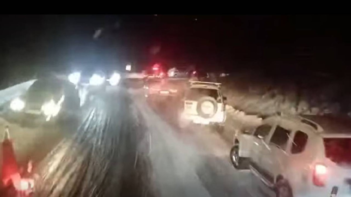 Mai multe mașini sunt oprite pe marginea șoselei pe un drum înzăpezit
