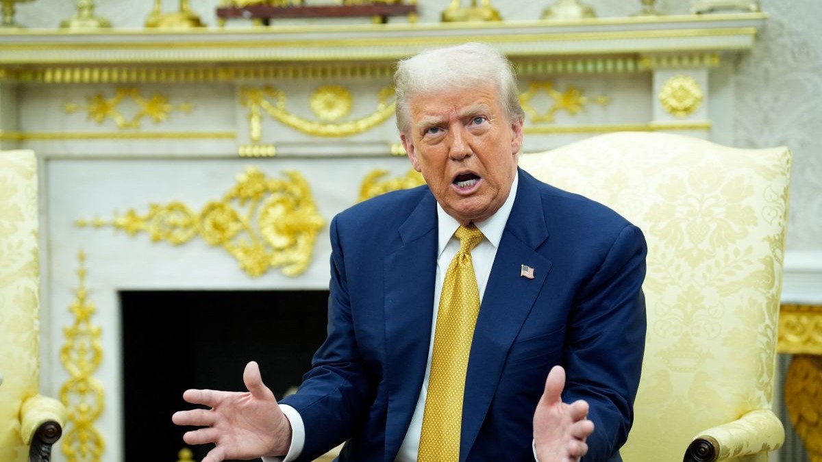Donald TRump, îmbrăcat la costum și cu cravată galbenă la gât, dă din mâini în timp ce vorbește stând pe un fotoliu de la Casa Albă, iulie 2025