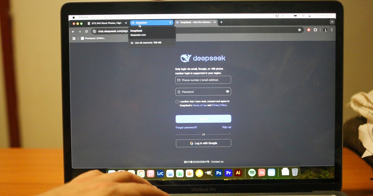 Mâna unui bărbat, așezată pe o tastatură de laptop MacBook Pro, pe care este deschisă o pagină web cu inteligența artificială DeepSeek.