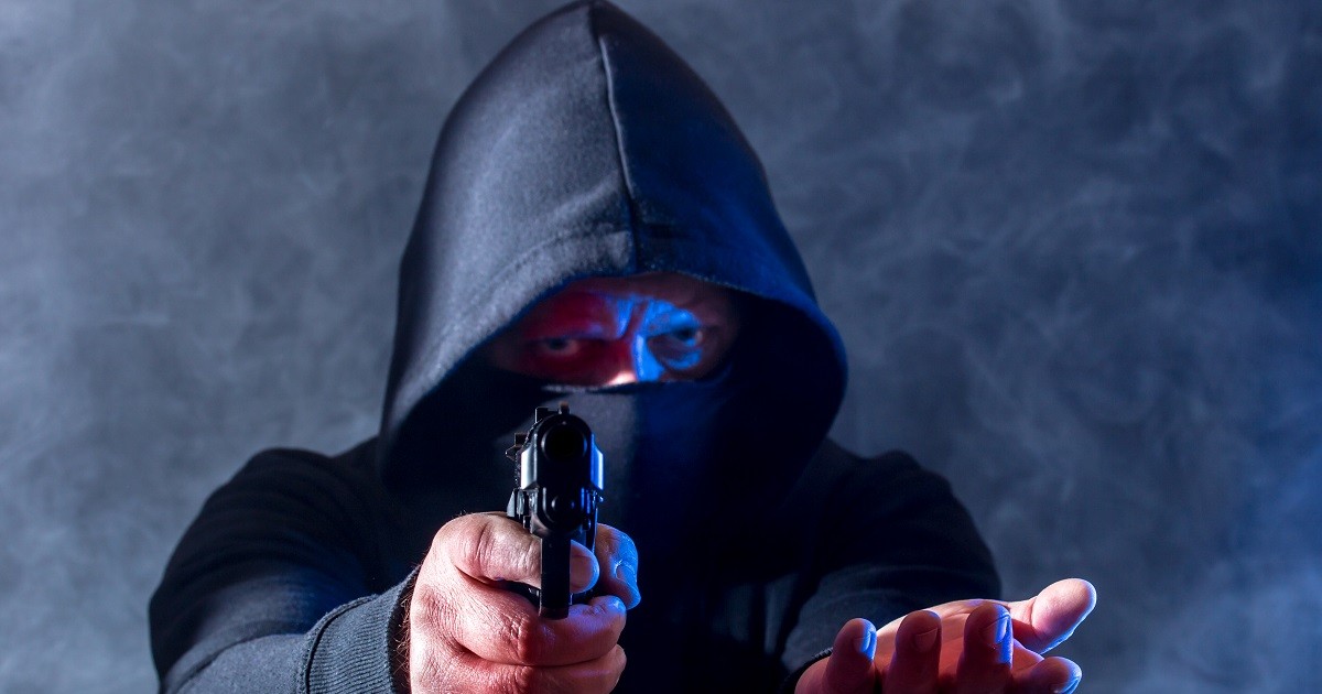 Bărbat cu un pistol în mână îndreptat spre obiectivul camerei de fotografiat